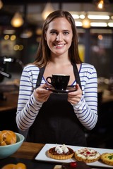 Smiling barista holding coffee