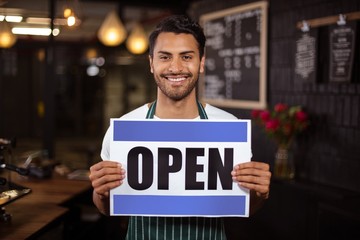 Smiling barista holding open sign