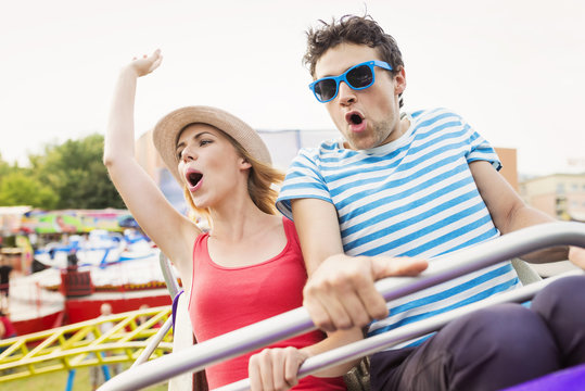 Happy couple at fun fair riding roller coaster