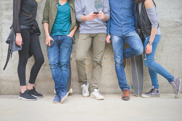 From the neck down view of a group of friends with skateboards h