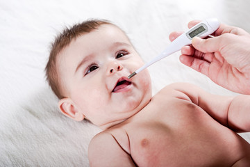 Doctor measures the temperature of little baby.