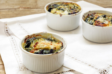 baked spinach with cheese in small casserole servings, white nap