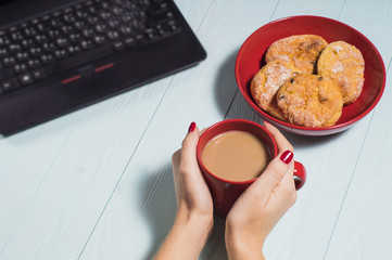 Female using laptop with a coffee cup on wooden table.