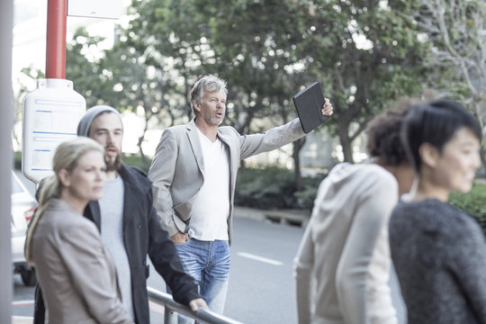 Mature man hailing a taxi at the roadside