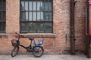 Fototapeta na wymiar Old bicycle and the old red brick buiding background