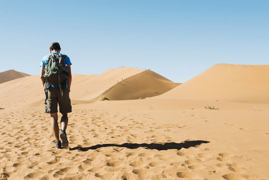 Namibia, Namib Desert, man with backpack walking through the dunes