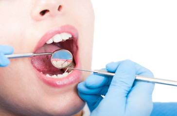 Dentist is looking into a female's mouth with dental mirror