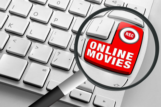 Computer keyboard with red online movies button and magnifying glass