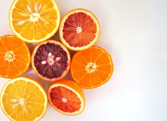 Ruby red blood oranges, navel oranges, and clementines cut in half on a white platter