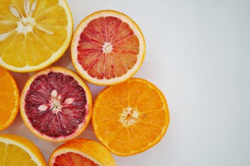 Ruby red blood oranges, navel oranges, and clementines cut in half on a white platter