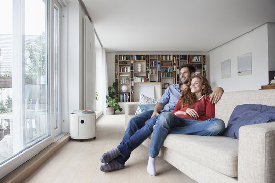 Relaxed couple at home on couch looking out of window