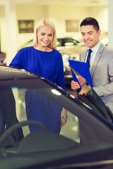 happy woman with car dealer in auto show or salon