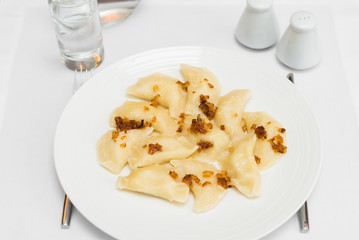 Russian dumplings with fried onion on white plate
