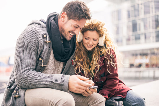 Italy, Milan, portrait of couple looking at smartphone