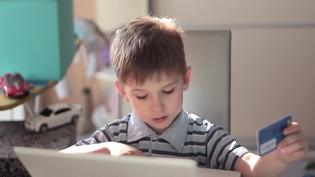 Cute little boy use laptop and credit card