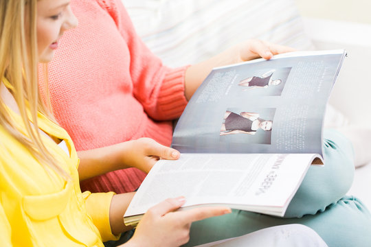 Close Up Of Happy Teenage Girls Reading Magazine