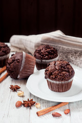 
pastries, chocolate muffins with almonds , hazelnuts , cinnamon and cocoa on a wooden background