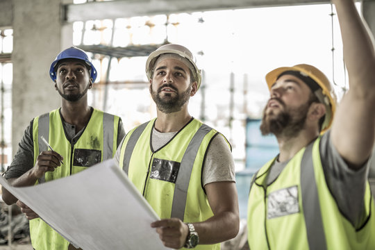 Construction workers discussing building plan in construction site