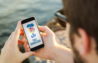 Man using his mobile phone on the coast to free download