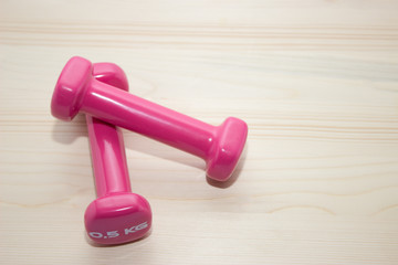 Two pink weights on wooden background