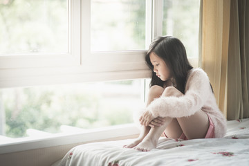Portrait of asian beautiful sad girl at the window