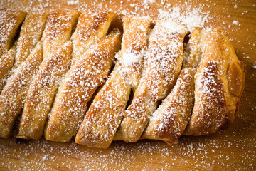 Uncooked homemade rustic apple pie preparation greased with egg yolk on white kitchen background
