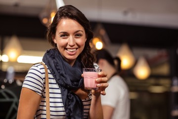 Smiling brunette drinking a beverage at the coffee shop