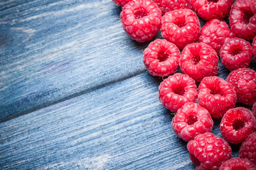 Fresh raspberries on blue wooden table.