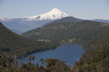 Lago y selva entre montañas con volcán Villarica nevado. Parque Nacional de Huerquehue, Chile
