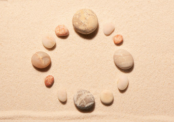 Round frame of sea stones on sand. Summer beach background