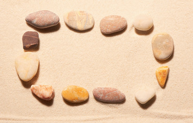 Fototapeta na wymiar Rectangular frame of sea stones on sand. Summer beach background