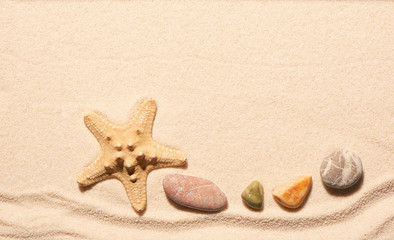 Fototapeta na wymiar Starfish and sea stones on sand. Summer beach background