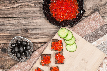 Toasts with red caviar on grunge wooden board