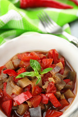 Ratatouille in bowl, on wooden table background