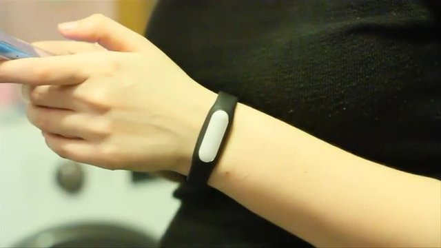 Female hands are typing on a smartphone touchscreen, smart band on a wrist