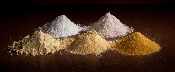Corn, rice and sorghum flours on a wood background