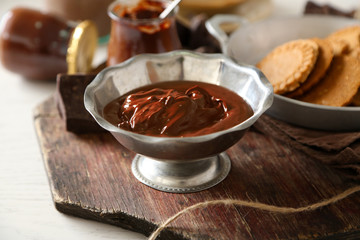Melted chocolate in bowl, on wooden background