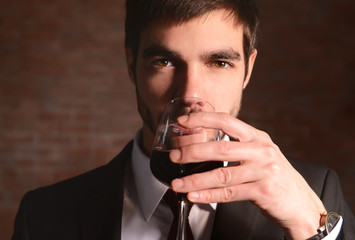 Man sniffing red wine in glass on brick wall background