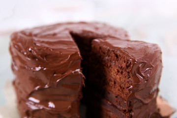 Chocolate cake with a cut piece on wooden table background, closeup