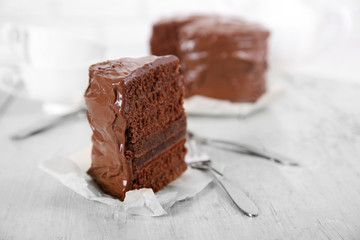 A piece of chocolate cake with forks on wooden table background, closeup