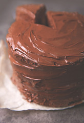 Chocolate cake with a cut piece and blade on gray background, closeup