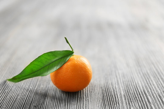 Fresh tangerine with leaf on wooden table, closeup