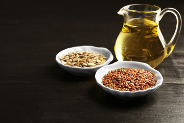 Flax and sunflower seeds with oil on wooden table