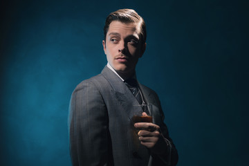 Vintage 1940s fashion man in suit and tie holding glass of whisk