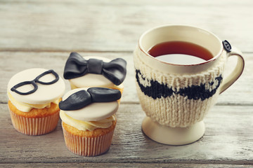 Delicious creative cupcakes and cup of tea on wooden table