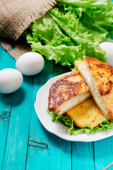 
sandwich with cheese and mayonnaise fried in egg with lettuce on a wooden background