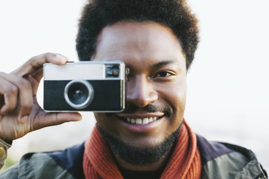 Portrait of smiling young man holding old camera
