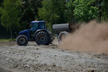 A farmer spreads blood and bone fertiliser on a paddock before planting new pasture, West Coast, New Zealand