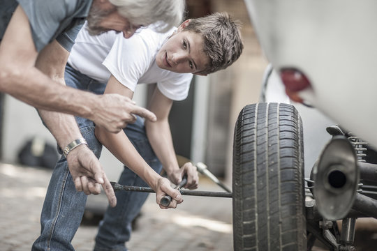 Grandfather and grandson changing car tire