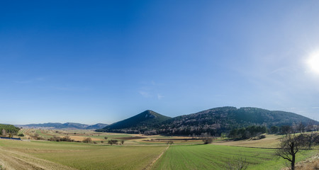 grosser gruener berg in landschaft panorama